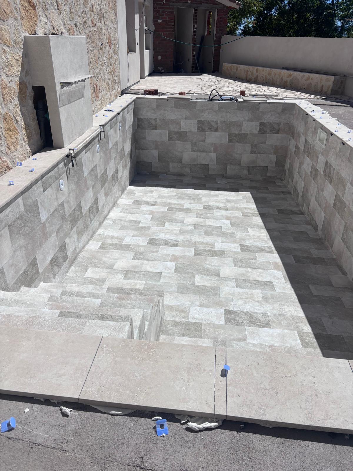 Piscina en construcción: obra de hormigón e impermeabilización con azulejos. Servicios profesionales de piscinas.