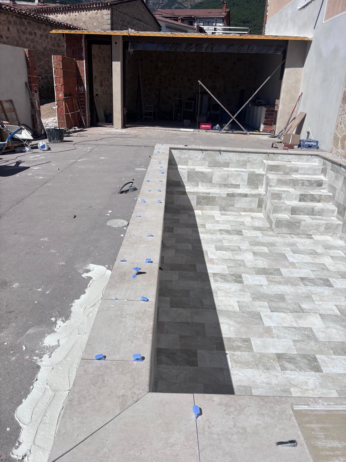 Piscina de hormigón en construcción. Obra de impermeabilización con alicatado interior en proceso.