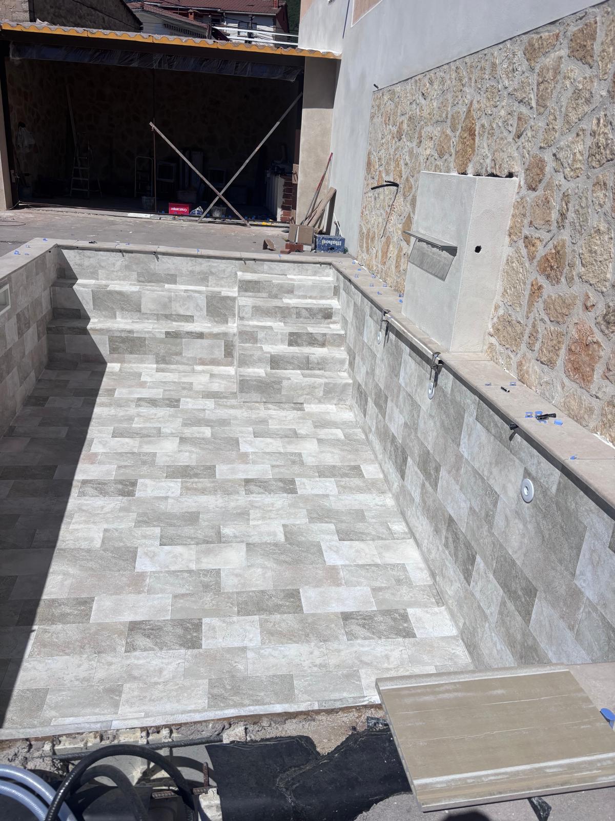 Piscina de hormigón en construcción, con azulejos grises. Obra avanzada de impermeabilización. Construcción y reforma de p...