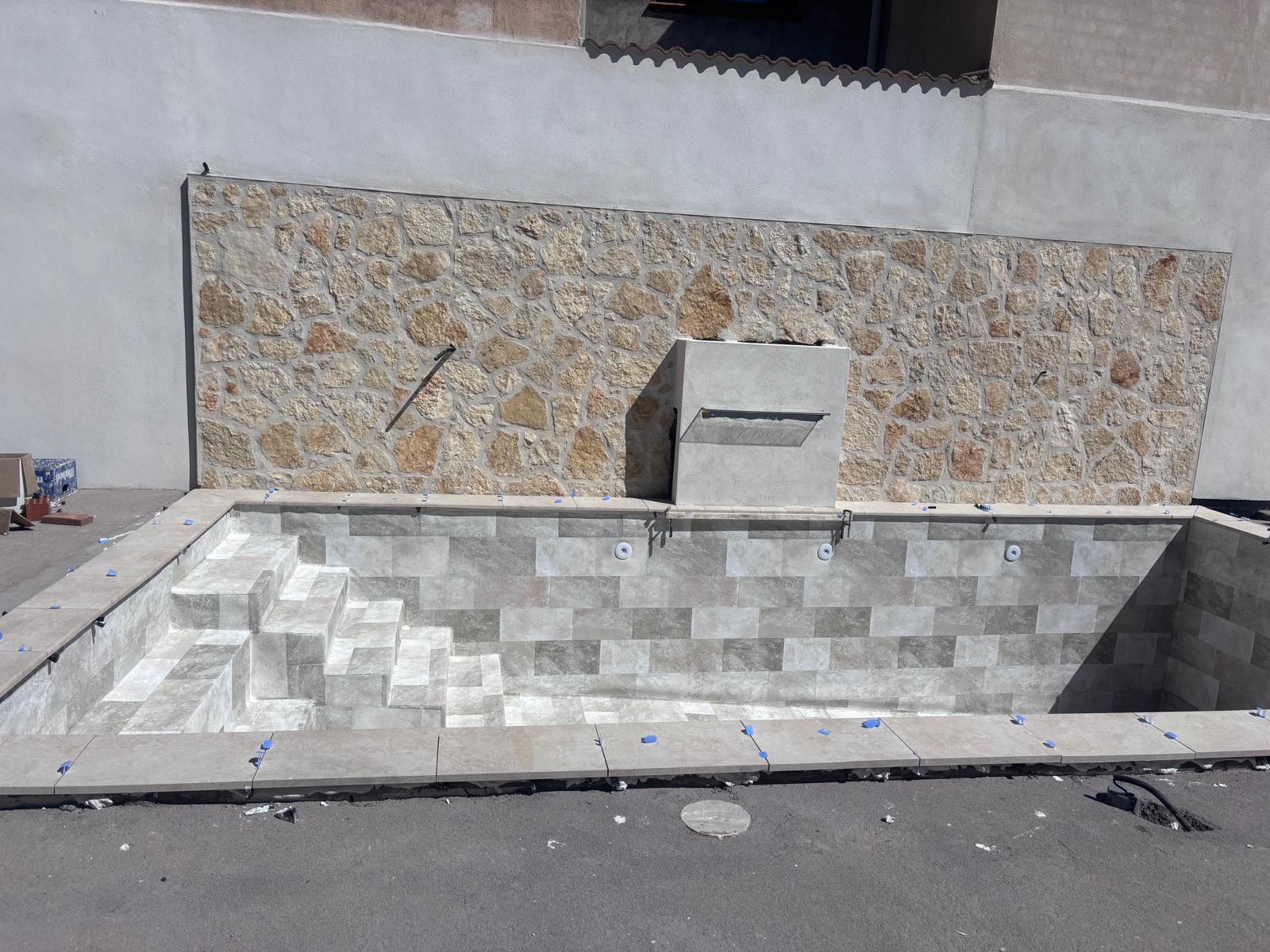 Piscina de hormigón en construcción. Obra de impermeabilización y acabados con azulejos. Diseño moderno.
