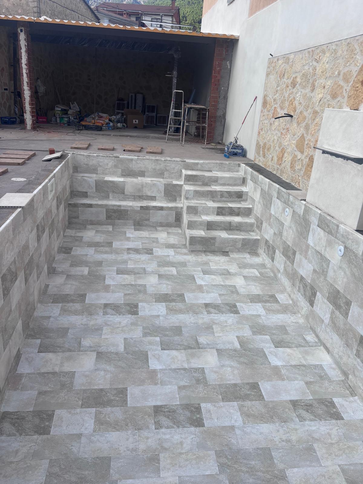 Obra y construcción de piscina de hormigón. Impermeabilización avanzada para piscina moderna con escaleras.