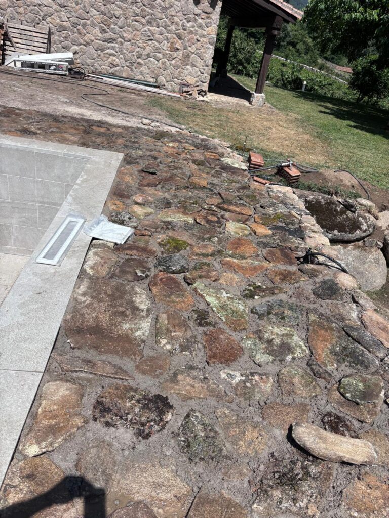 Piscina en construcción con impermeabilización, obra de hormigón y pavimentación de piedra.
