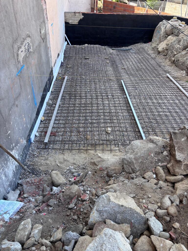 Piscina en construcción. Cimentación de hormigón y mallazo para impermeabilización en obra.