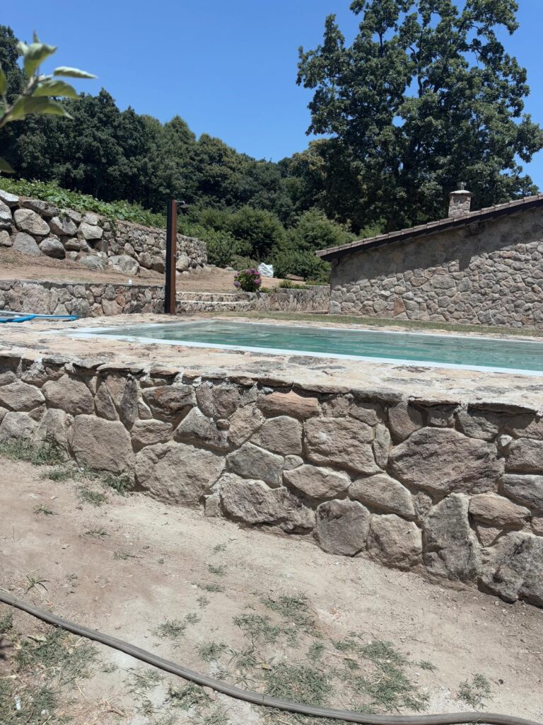Construcción de piscina de hormigón con impermeabilización. Obra rústica con muros de piedra.