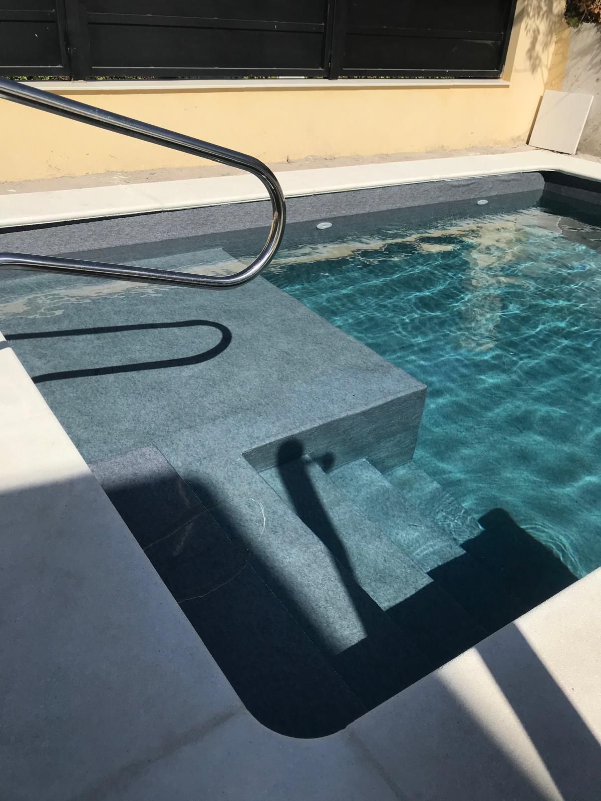 Piscina de hormigón con escaleras y barandilla. Expertos en construcción e impermeabilización de piscinas de obra.