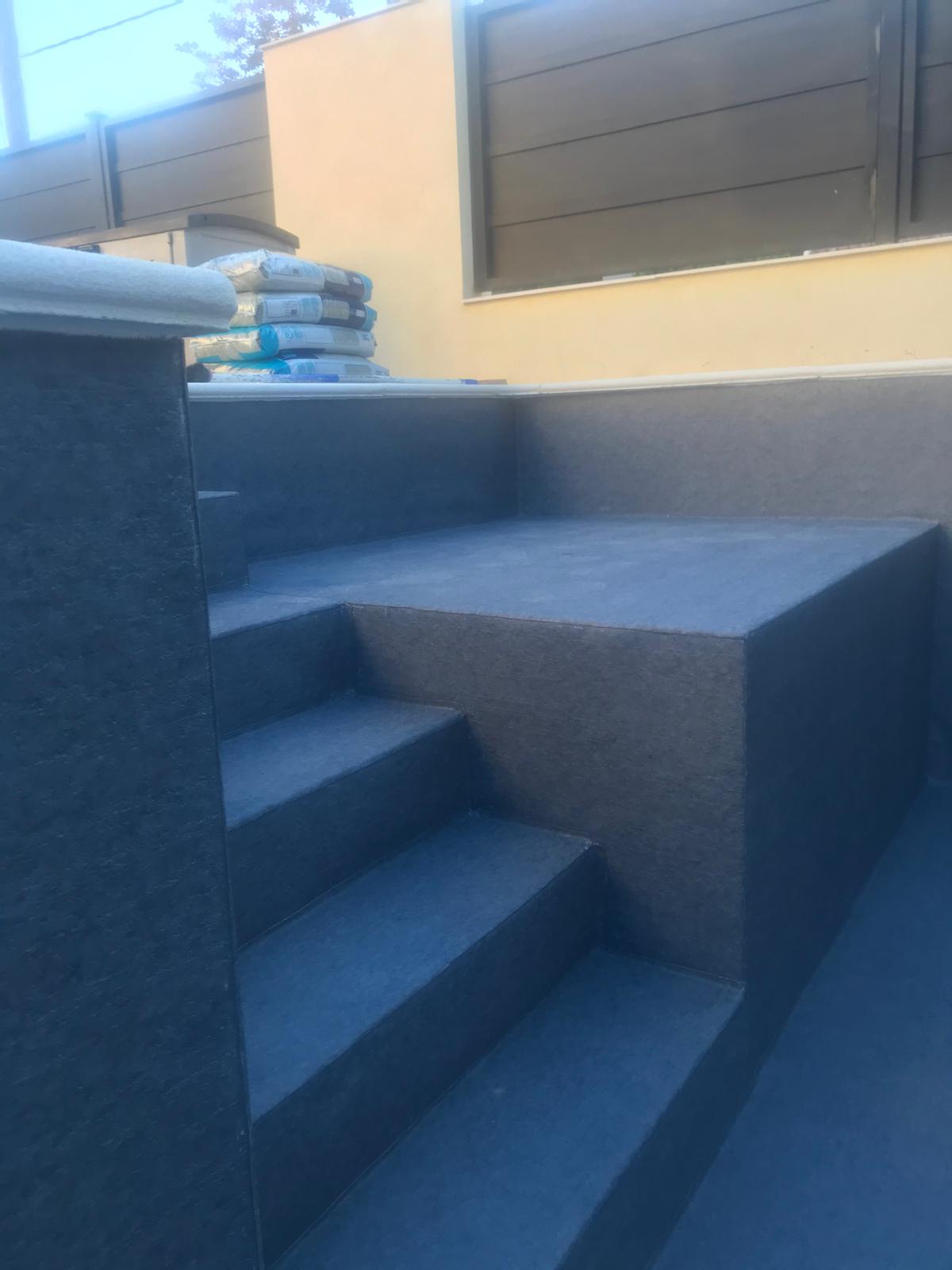 Piscina de hormigón en construcción. Impermeabilización aplicada en obra, con escaleras y zona de descanso.