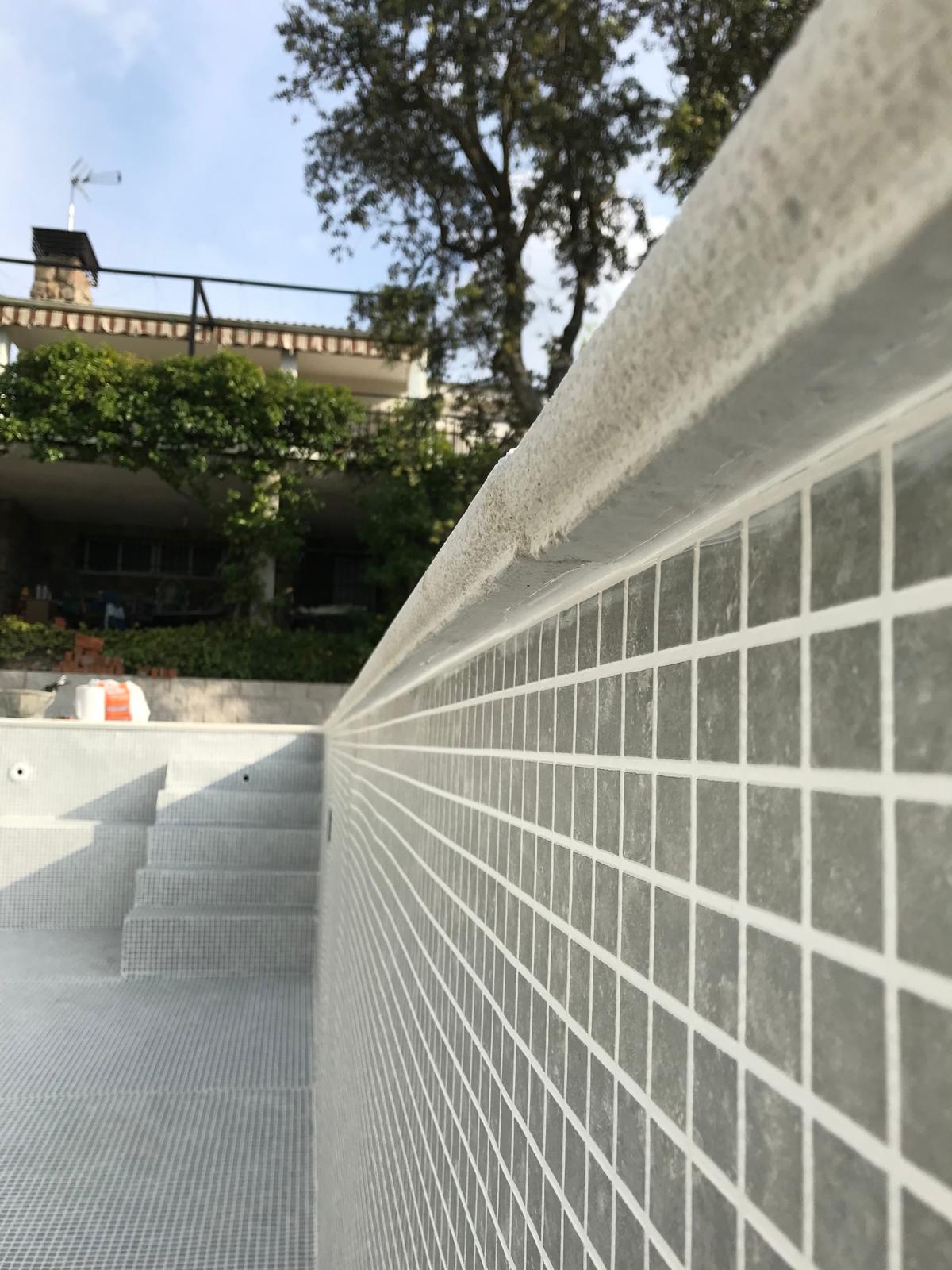 Piscina de hormigón en construcción, obra con mosaico gris y escaleras. Impermeabilización profesional.