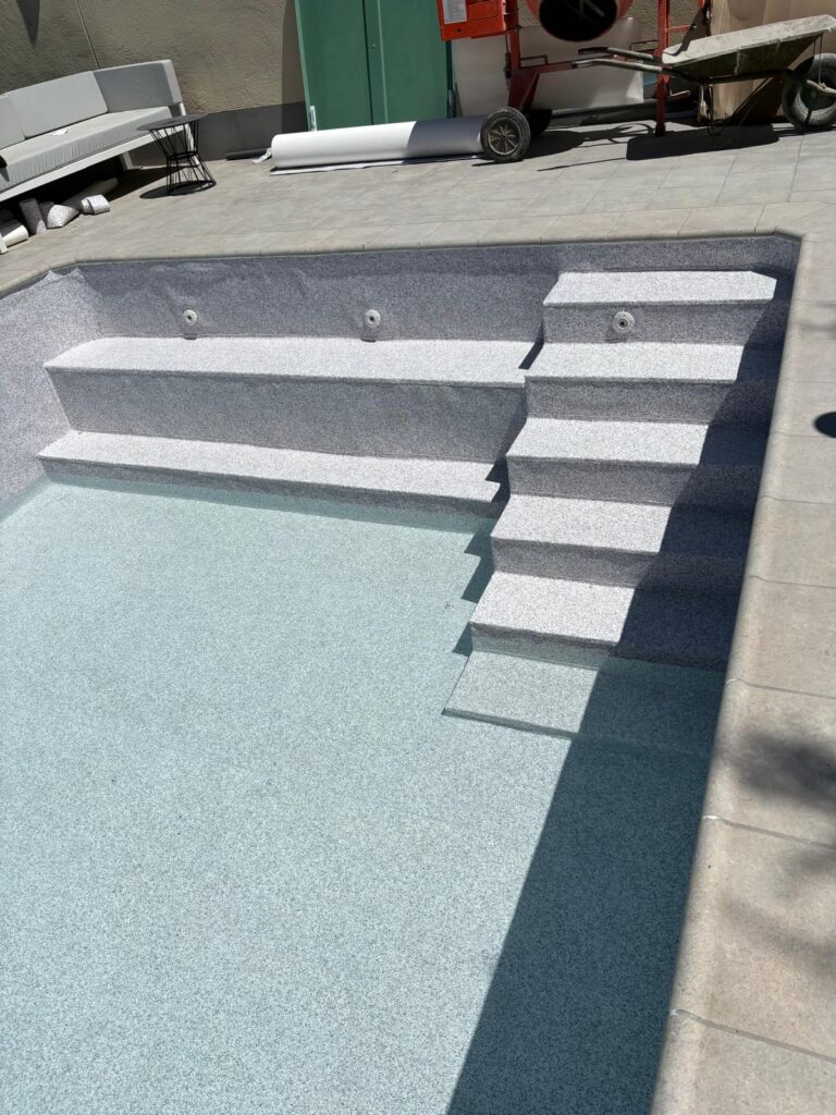 Construcción de piscina de hormigón. Obra con impermeabilización, revestimiento y escaleras de piscina.