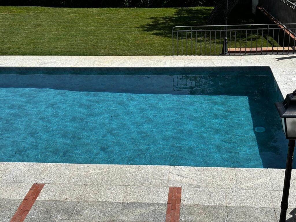 Piscina de hormigón azul, obra de construcción e impermeabilización de calidad para tu jardín.