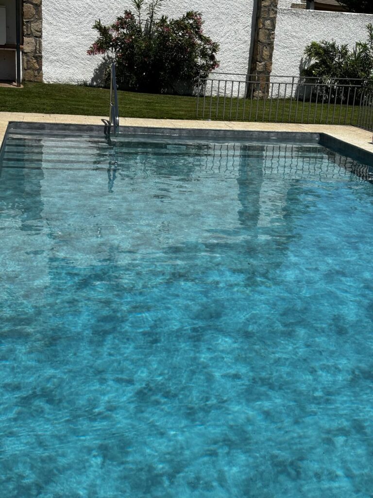 Piscina de obra de hormigón con agua azul. Expertos en construcción e impermeabilización de piscinas.